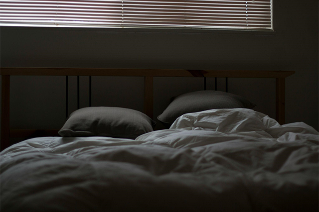 つらくて薄暗い部屋のベッドのイメージ