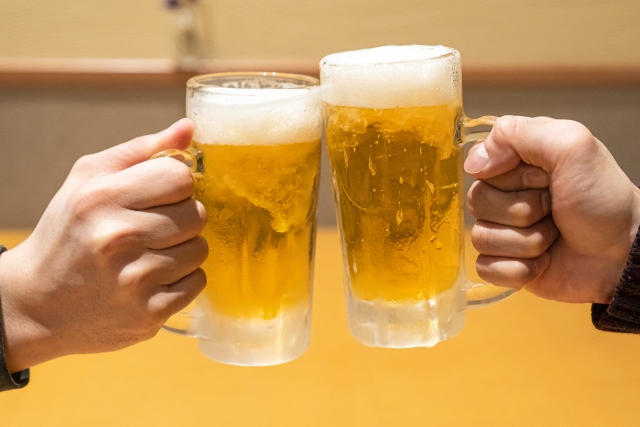 ジョッキに入ったビールで乾杯する二人の手。一度退職した会社に再入社した理由についての説明。