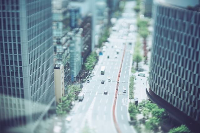 高層ビルに囲まれた都会の道路の風景。一度退職した会社に再入社した理由についての説明。