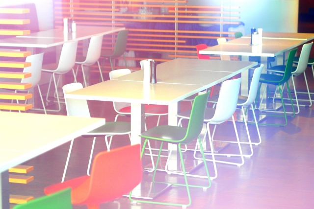 色とりどりの椅子が並ぶ明るいカフェテリアの風景。