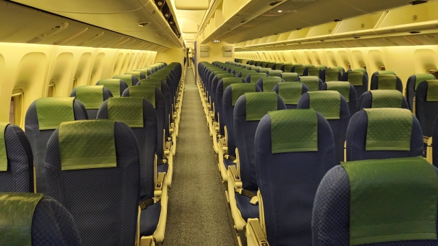 機内の空の座席が並ぶ通路の風景。