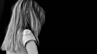 黒い背景に背を向ける金髪の少女。ブログ「インナーチャイルドは3人いた！“あの頃の私”に出会って見つけた『自分の本音』」に関連する画像