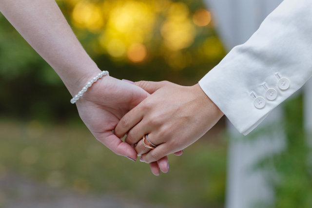 結婚式で手を繋ぐ新郎新婦の手のクローズアップ。