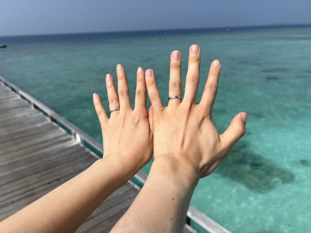 海を背景に並べた2人の手、それぞれに結婚指輪が見える。ブログ「統合失調症を持つ私の結婚に対する周囲の反応」に関連する画像。