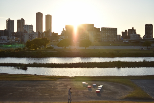 夕日が沈む都市の風景と川。25年間続けた「あはき業」から離れた全盲の人のストーリー。