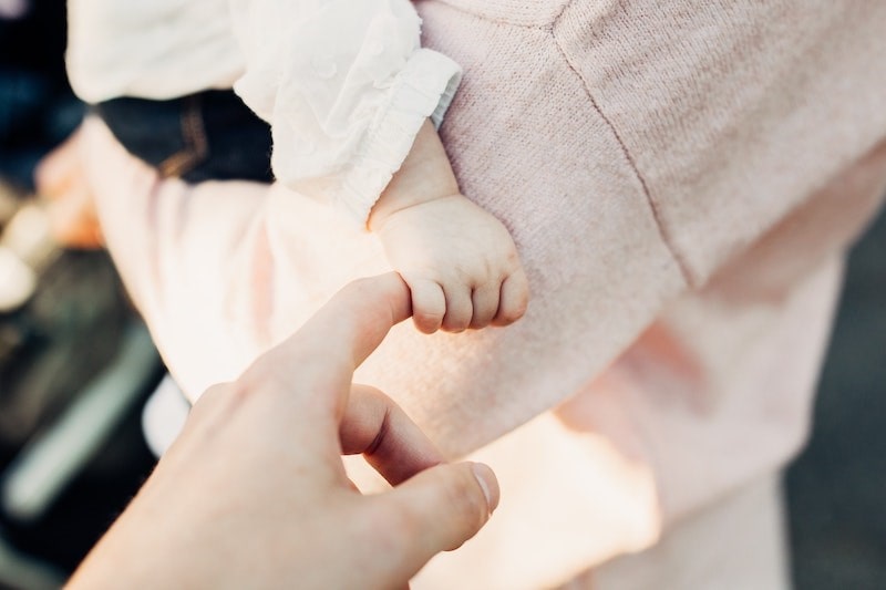 赤ちゃんが大人の指を握っている写真