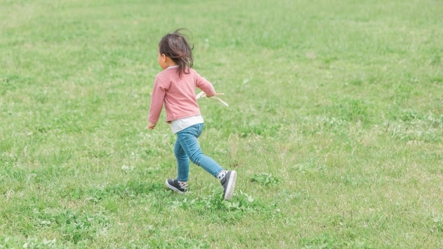 広い芝生の上を走る子供。