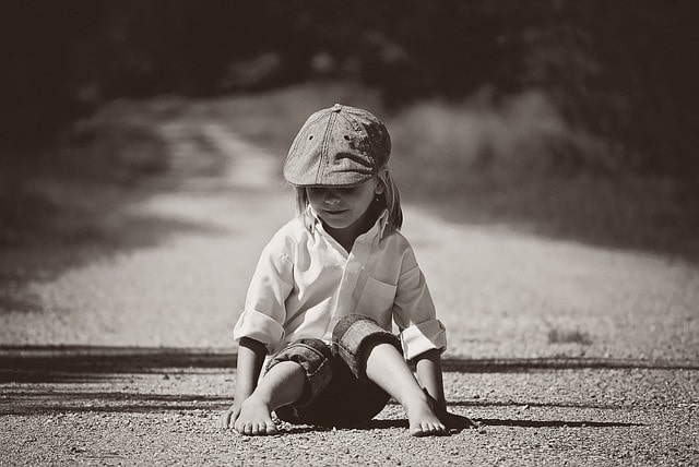 帽子をかぶり、砂利道に座っている子供。「不幸」であることが当たり前だと思っている状態について考察する内容に関連する画像。