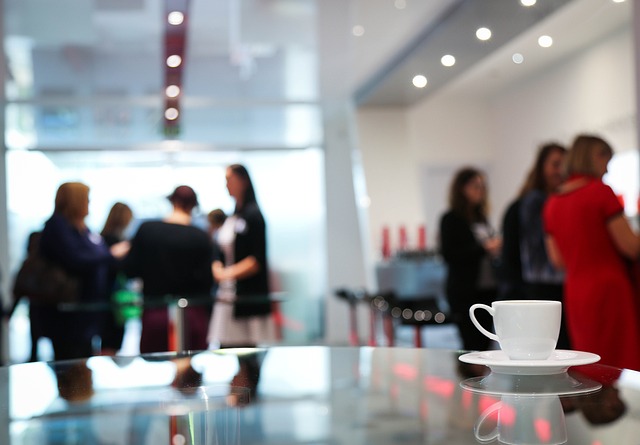 カフェでの会議中の人々と前景のコーヒーカップ。