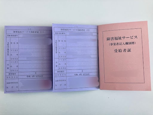 障害福祉サービスの受給者証と申請書類の写真。