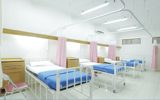 複数のベッドが整然と並べられた白い病室