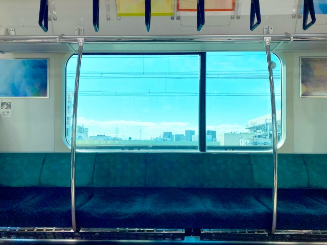 空の電車の車両内と大きな窓からの景色。通勤時のパニック障害の症状と向き合うシーンを表しています。