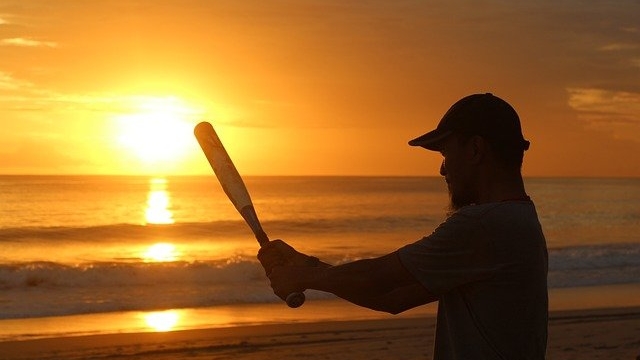 夕焼けのビーチで野球をしている男性のシルエット