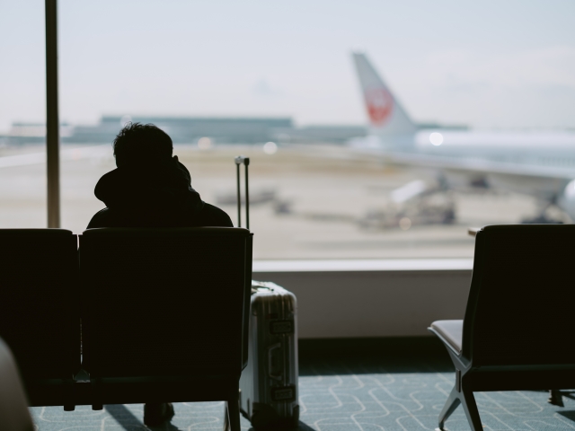 空港の待合室で飛行機を待っている男性の後ろ姿。