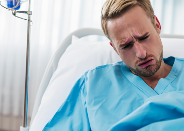 病院のベッドで苦しそうな表情をする男性患者。ブログ「精神科病棟はロボットの修理工場ではない」に関連する画像。