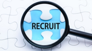 拡大鏡で「RECRUIT」と書かれたパズルのピースを拡大している画像。障がい者の就職フェスに関連する企業のニーズを示唆。