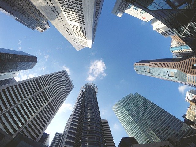 都市の高層ビル群を下から見上げた風景。青い空とビルの対比が印象的。