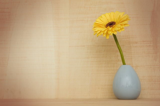 青い花瓶に活けられた黄色いガーベラの花