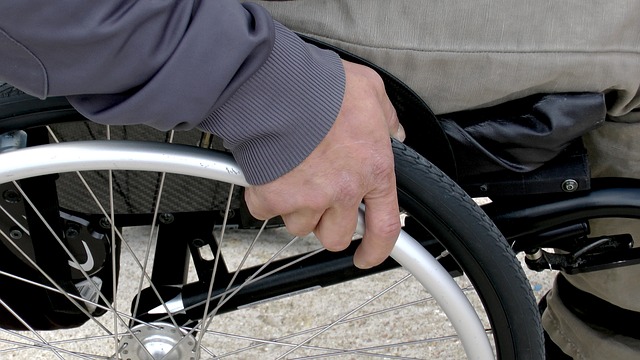 車椅子の車輪に手をかけている人のクローズアップ。