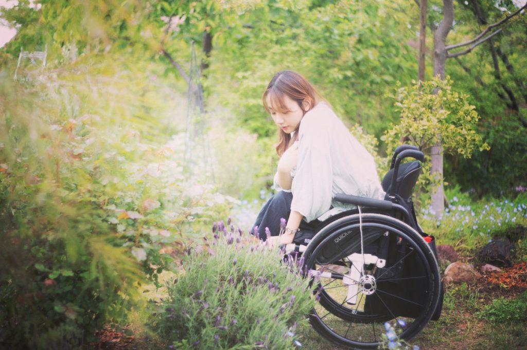 豆塚さんが紫の小さな花を見ているイメージ