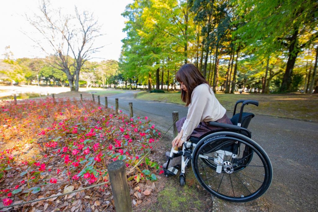 豆塚さんが車椅子から赤い花を見ている様子