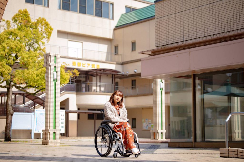 施設の外にいる車椅子姿の豆塚さん