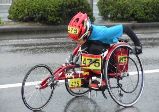 大分国際車いすマラソンで豆塚さんが雨の中必死で走っているイメージ