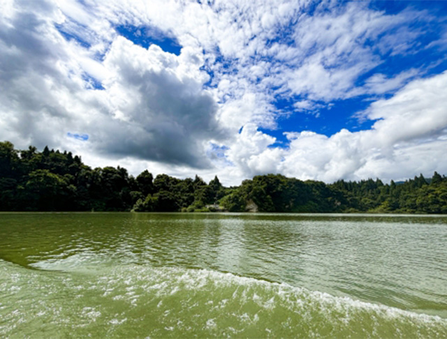 湖とその周囲の森、青空に広がる雲の美しい風景画像。自然の静けさと雄大さを感じるシーン。