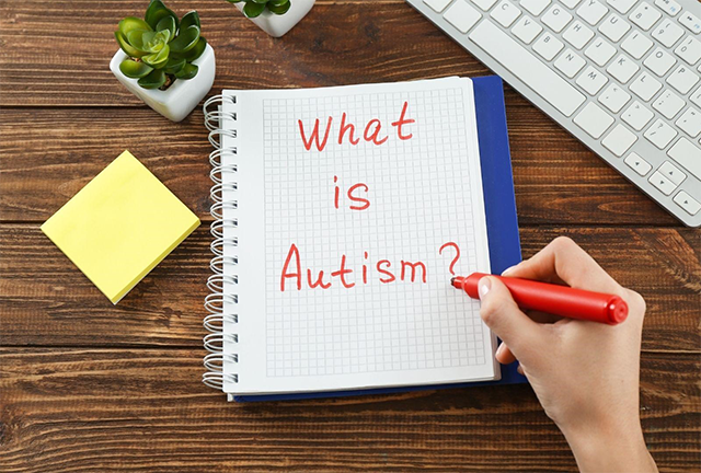  ノートに「What is Autism?」と書かれているシーン。ASD（自閉症スペクトラム障がい）について学ぶための問いかけを象徴するイメージ。