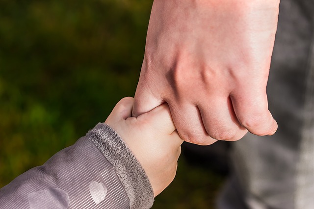 子どもが大人の指をしっかり握っている様子。